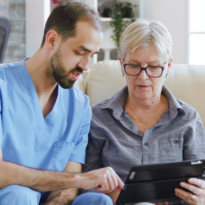 man teach the elderly woman to use gadget